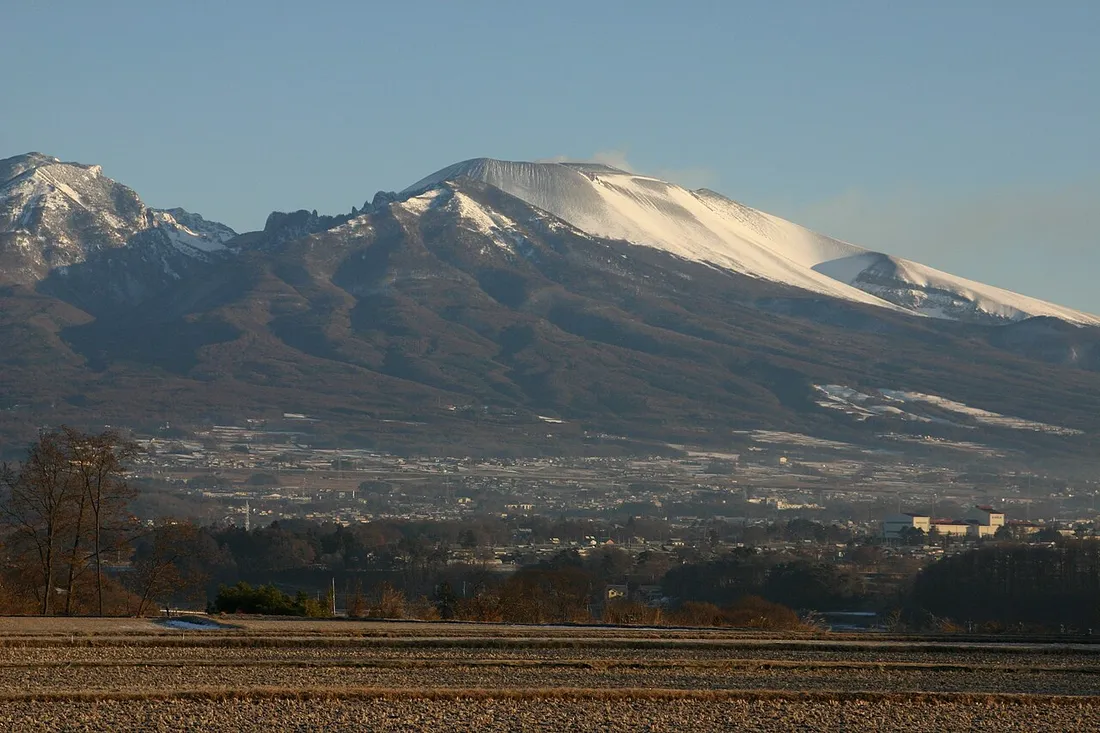 佐久方面から見た浅間山。山頂付近に雪が見え、手前に畑が広がる