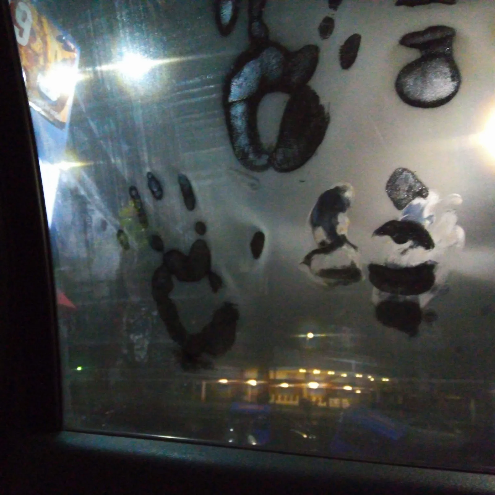 夜の車内から見た窓ガラスが結露で白く曇り、指で描いた模様の部分だけ外の明かりが透けて見える