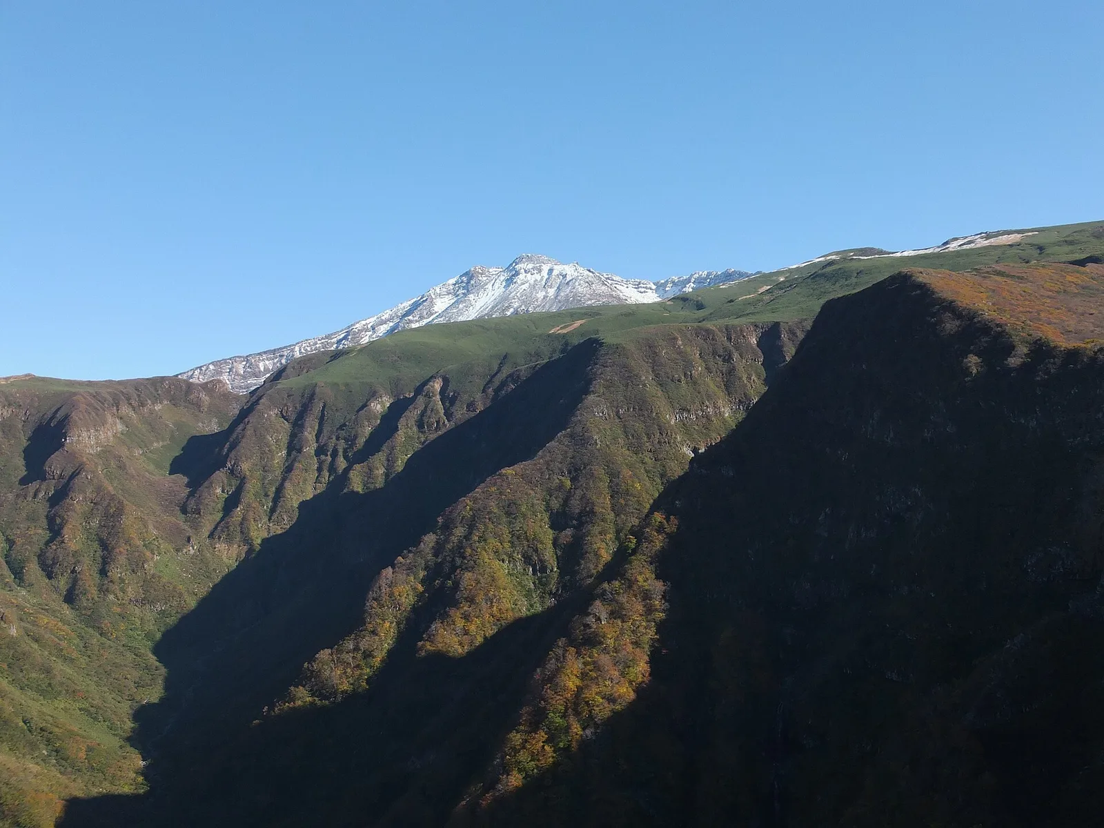 10月の鳥海山。紅葉した斜面と雪をかぶった山頂部
