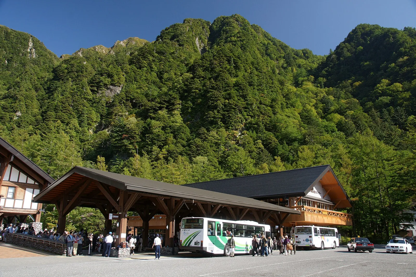 山を背にした上高地バスターミナルの建物と、停まっているバス