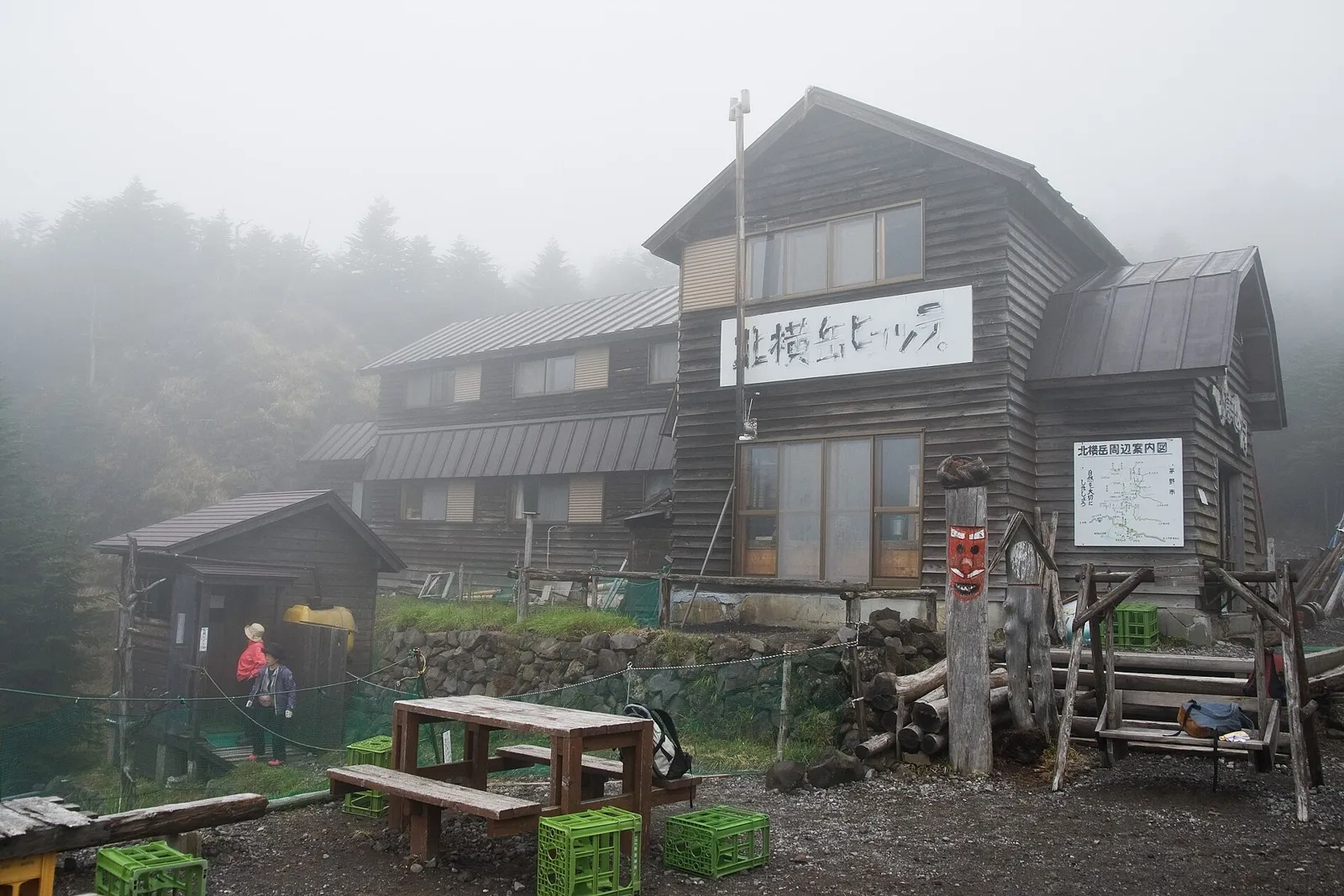 霧の中の北横岳ヒュッテの建物と前のベンチ
