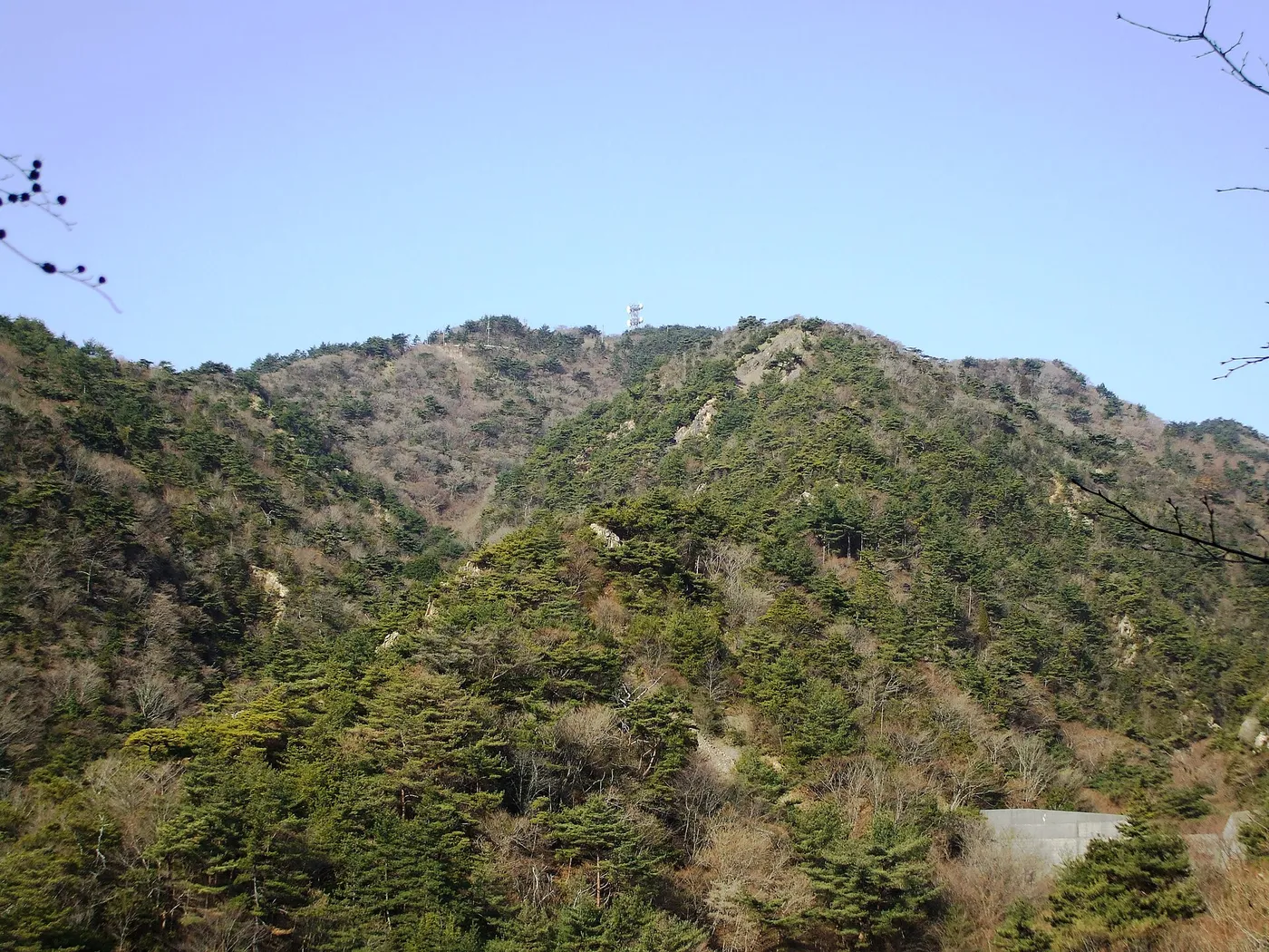 The rounded, partly wooded summit of Mount Rokko seen from the southeast under a clear winter sky