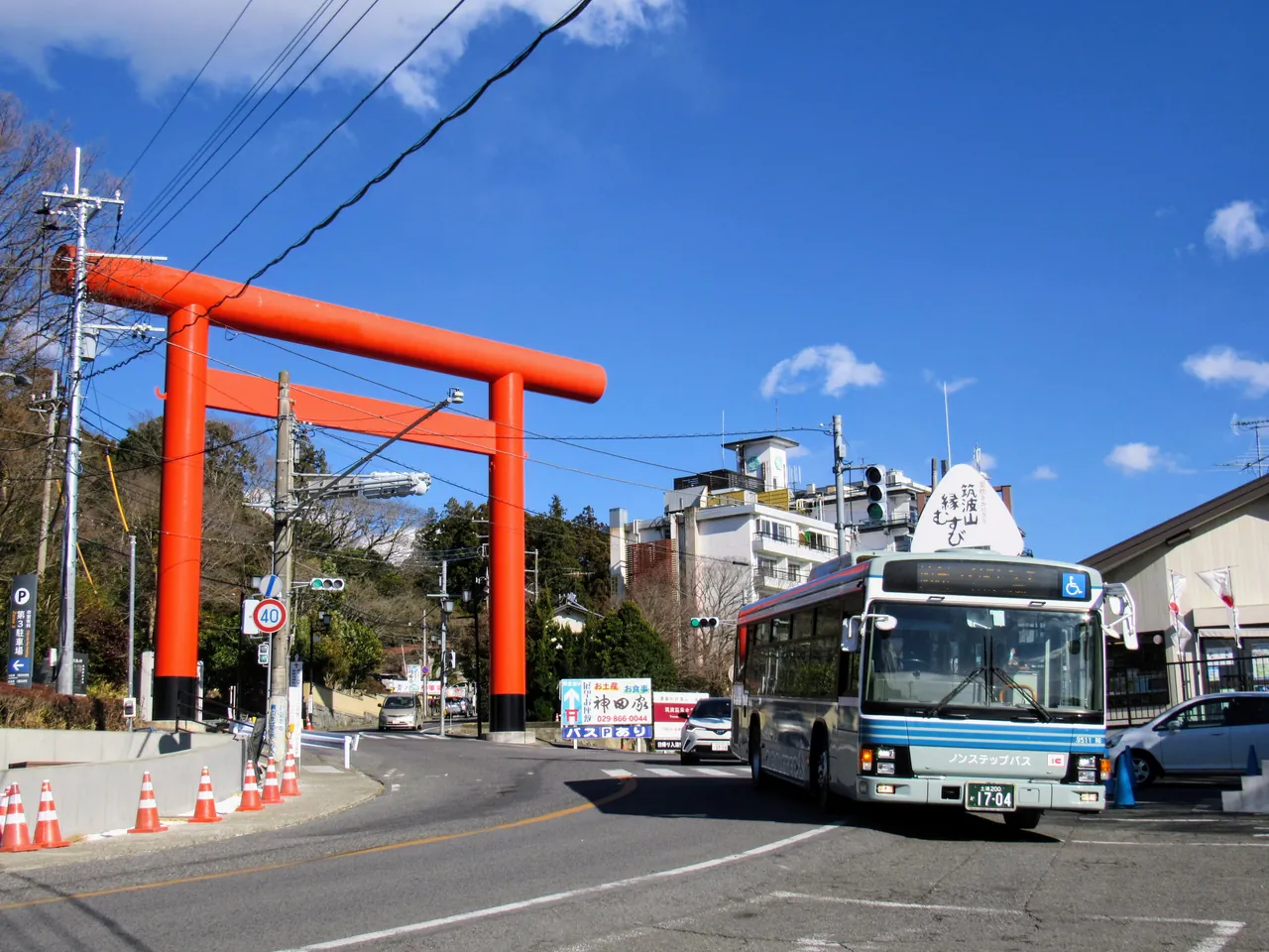 蓝白配色的关东铁道路线巴士行驶在道路上，背后是一座高大的红色鸟居