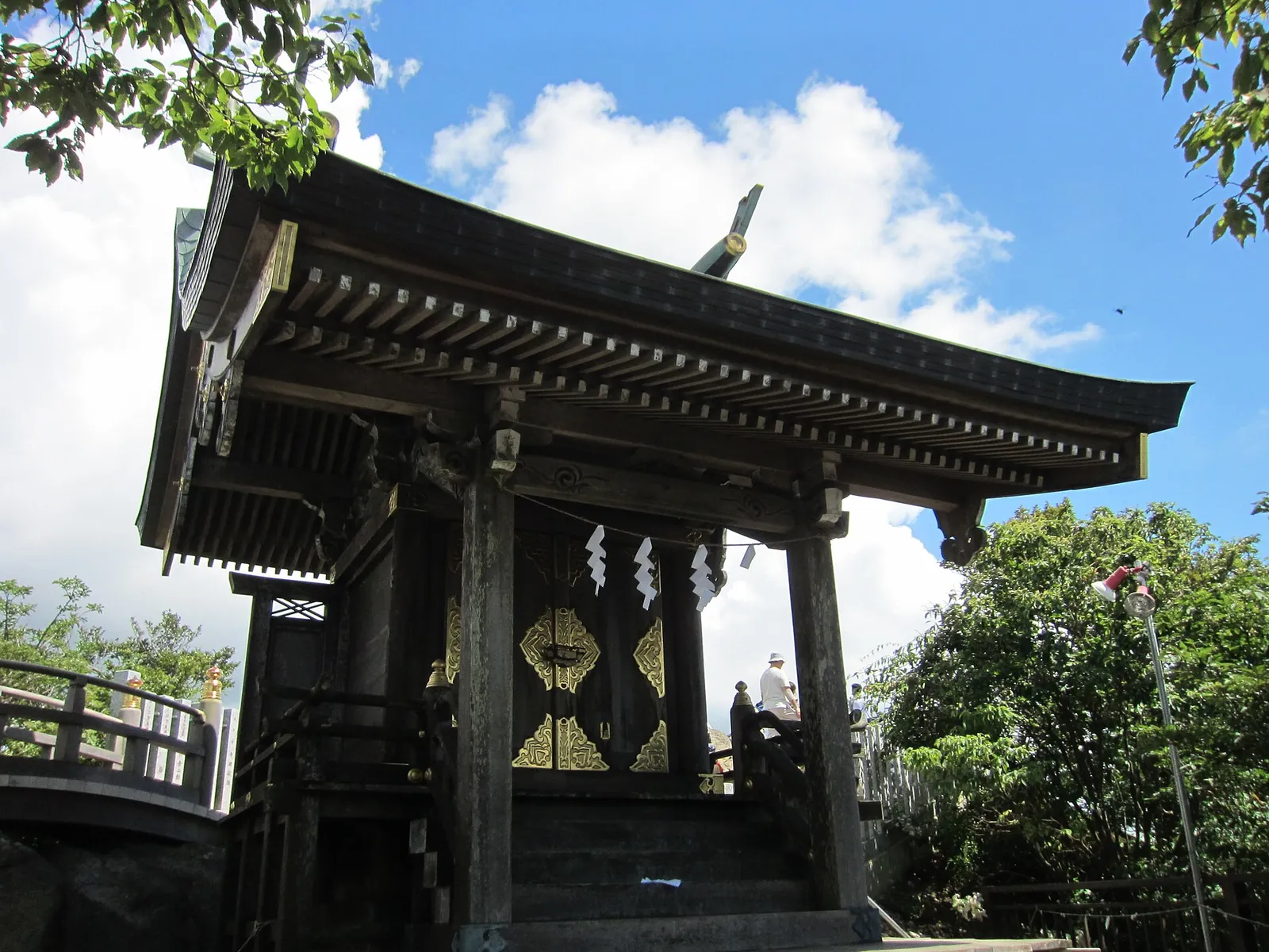 The small wooden honden shrine on the summit of Nyotaisan under a blue sky