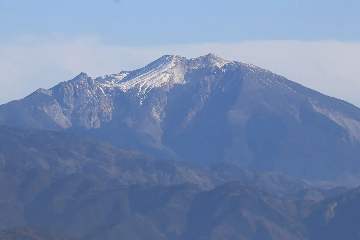 雪をかぶった御嶽山の山頂部を遠くから望む
