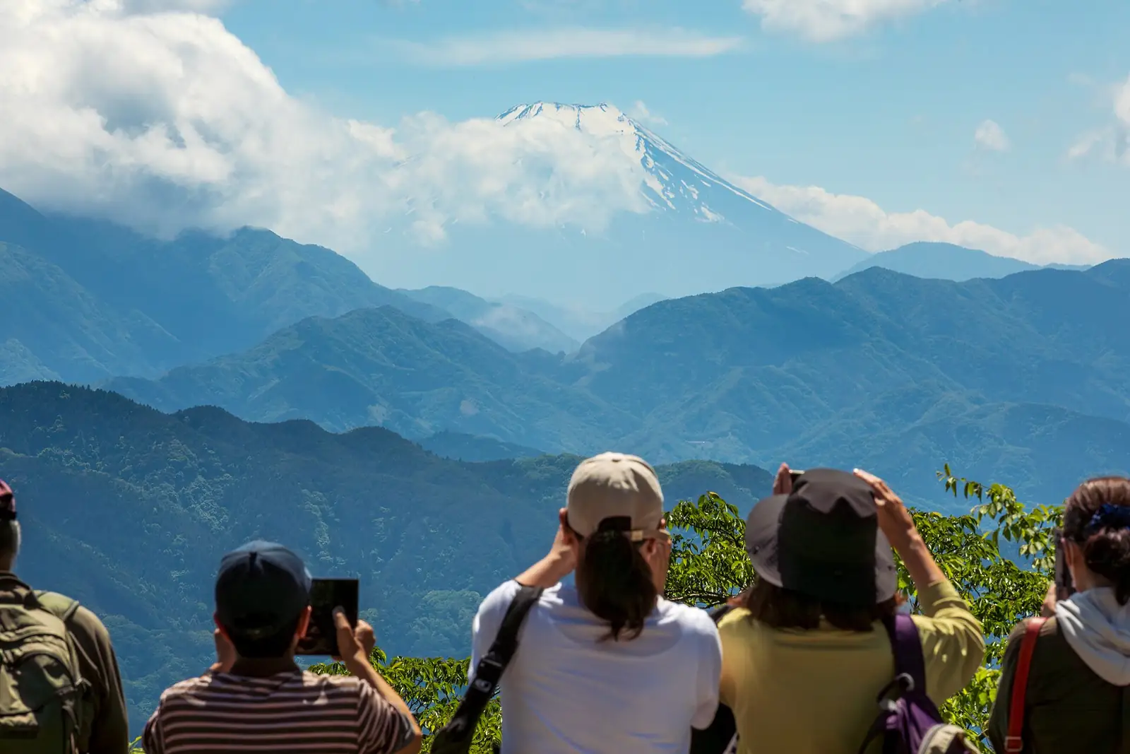 高尾山山頂上的人們眺望遠處的富士山和層層山巒