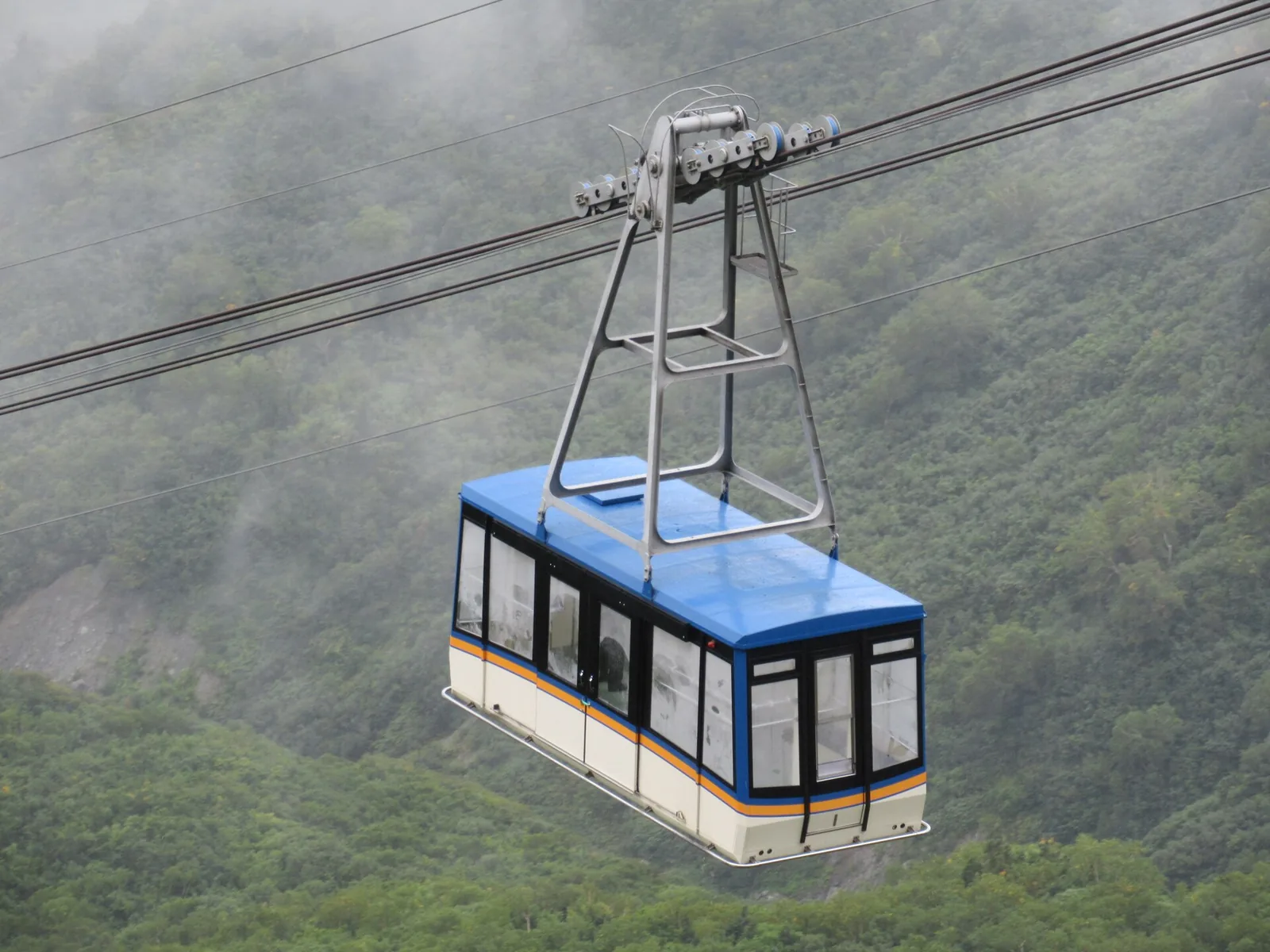 悬在空中的立山索道车厢，背景为山坡