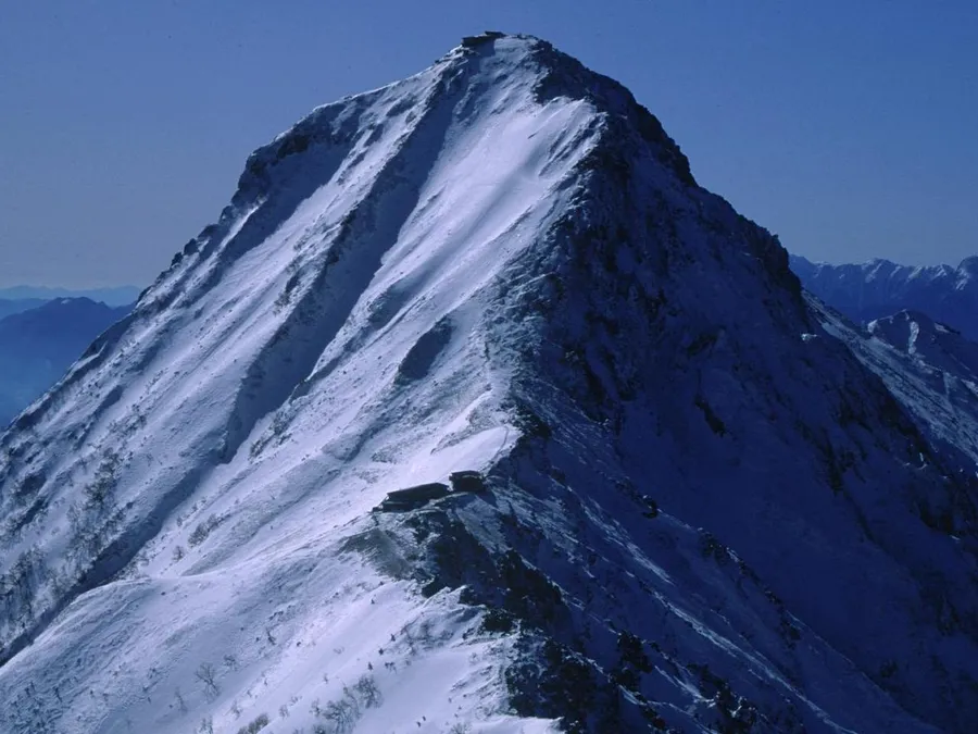 雪をまとった赤岳の山頂部。青空の下で鋭くそびえる