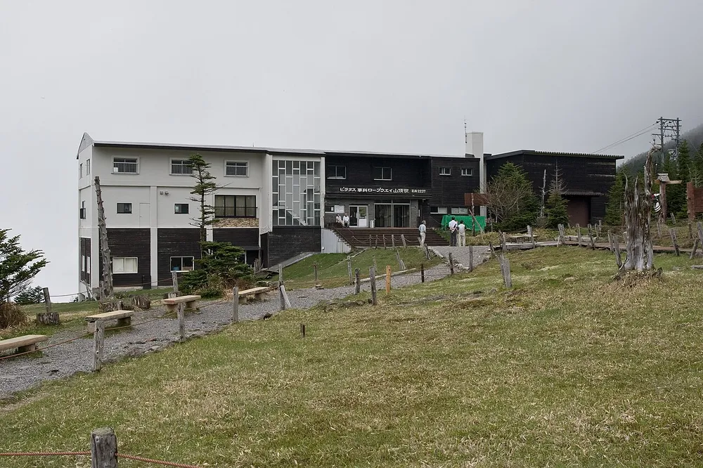 北八ヶ岳ロープウェイの駅舎と、手前に広がる草地。空は曇っている