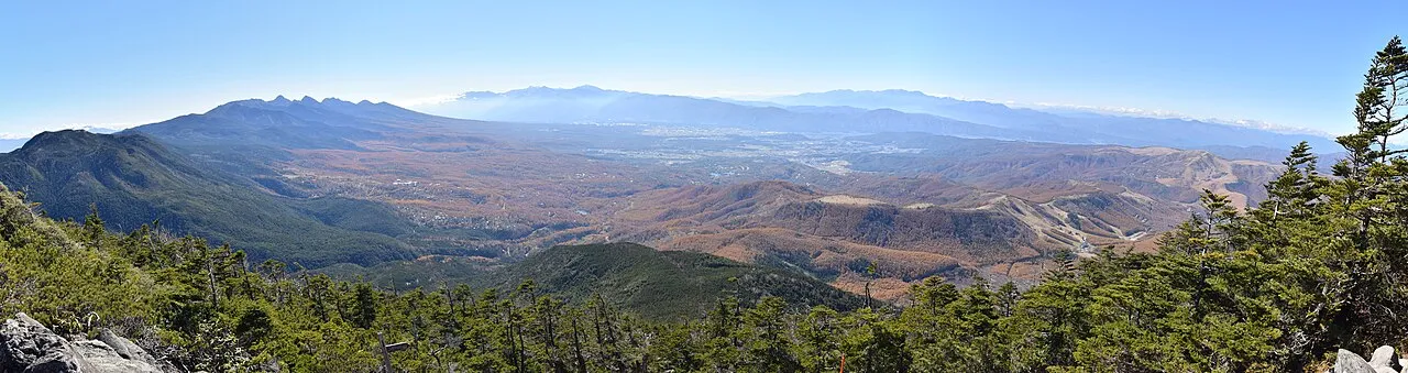木々の向こうに広がる、蓼科山方面の高原と山並みのパノラマ